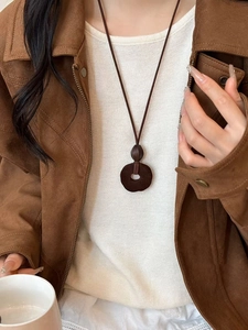Close-up of vintage resin necklace pendant on model wearing brown velvet jacket