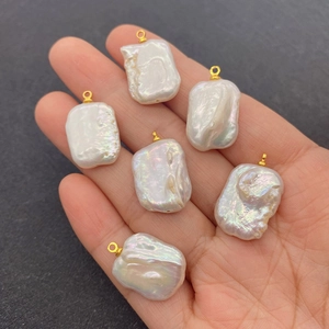Hand holding six baroque irregular freshwater pearl pendants with gold connectors