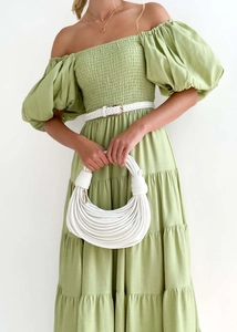 Detail of off-shoulder green maxi dress with layered ruffle skirt and woven belt