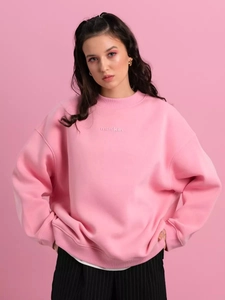 Detailed view of pink crewneck sweatshirt with maskin letter print and soft fabric texture