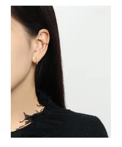 Close-up of gold geometric earrings and sparkling ear cuff set on model's ear