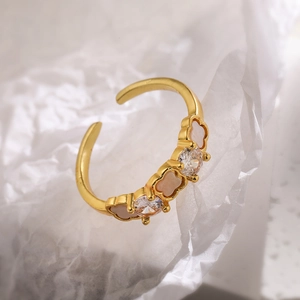 Macro detail of gold plated clover ring with zircon stones on white crumpled paper