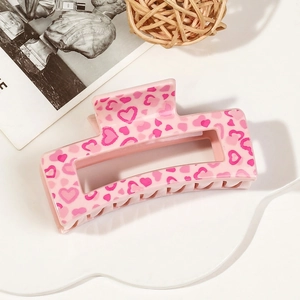 Close-up of a pink rectangular hair claw clip featuring a romantic heart pattern
