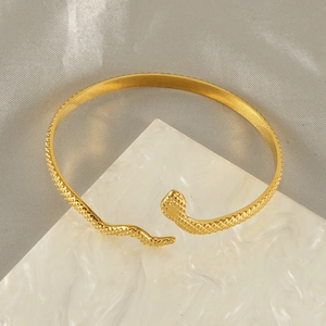 Bracelet serpent ouvert doré avec texture d'écailles sur un fond en pierre élégant