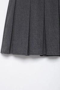 Macro view showing deep grey pleated fabric texture and hem detail of women's skort