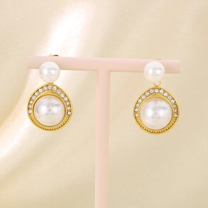 Détail de boucles d'oreilles perles dorées avec strass sur un support à bijoux rose