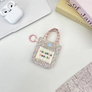 Floral mini pouch with pink handle and clip for earphones or lipsticks on a desk