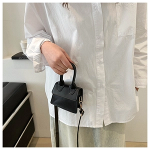 Nahaufnahme einer stylischen schwarzen Mini-Umhängetasche aus Leder, von Model gehalten