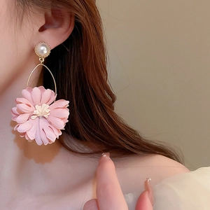 Detail showing oversized pink fabric flower earrings with pearls on a female model