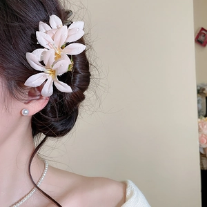 Detail of pink lily hair pin with dewdrop effect and matching pearl jewelry on model