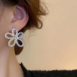 Elegant silver flower stud earrings with hollow petals and sparkling pavé diamonds on model
