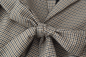 Detailed close-up of brown houndstooth fabric texture with a stylish knotted bow design