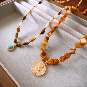 Detail of vintage layered beaded necklaces with tiger eye stone and gold coin pendants
