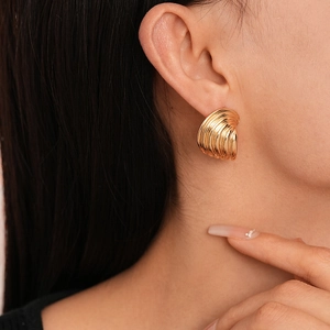 Macro side view of golden irregular wavy shell earrings with metallic texture