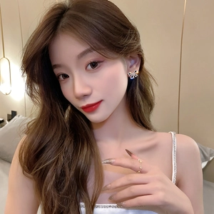 Close-up of elegant gold bow stud earrings with sparkling crystals worn by a model