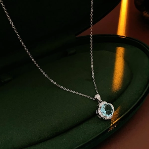 Close-up of blue zircon rose pendant with crystal halo in a premium green velvet box
