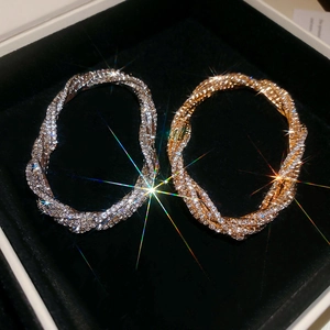 Macro view of gold and silver twisted multi-layer bracelets with sparkling rhinestones