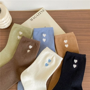 Detailed view of heart embroidered crew socks in multiple colors on wooden background