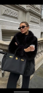 Détail d'un luxueux manteau en fausse fourrure noire avec sac à main et bijoux dorés