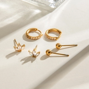 Détail de trois paires de boucles d'oreilles en acier inoxydable doré serties de zircons
