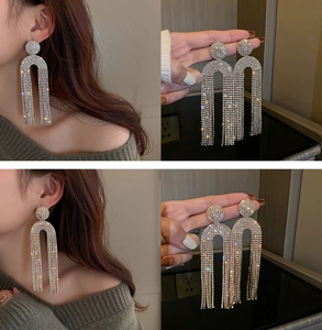 Macro shot of silver U-shaped tassel earrings featuring sparkling rhinestones and crystal details