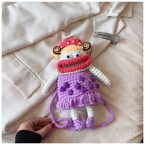 Detail view of a handmade crochet doll bag with purple body and pearl necklace accent