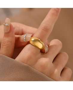 Close-up of a wide polished gold-plated stainless steel ring worn on a finger