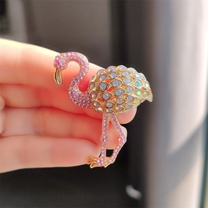 Detailed close-up of a golden flamingo brooch featuring sparkling pink rhinestones