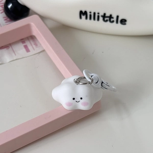 Close-up of white 3D cloud keychain with a cute smiling face and pink blush detail