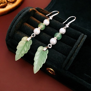Detailed view of vintage flower tassel earrings with green jade leaves in a black jewelry box