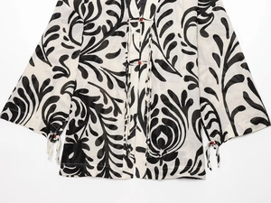 Detail of kimono style top featuring black and white leaf print with red bead buttons