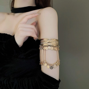 Bohemian gold arm cuff featuring layered chains and embossed coin pendants for women