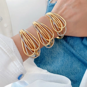 Fashionable 18K gold plated bangle with white zircons shown on a person wearing denim