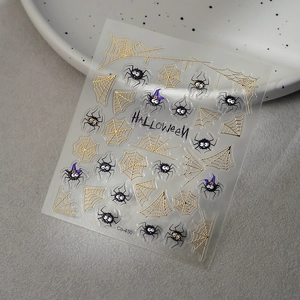 Halloween nail art stickers with golden spider webs and black cartoon spider patterns