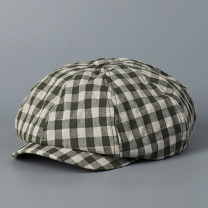 Close-up of green and white plaid linen newsboy cap with textured fabric and button top