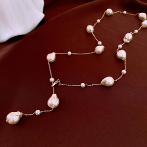 Detailed macro view of baroque pearl necklace laid on elegant dark red satin silk background