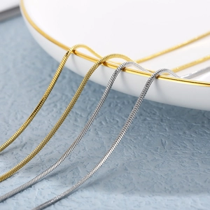Gold and silver snake chain necklaces draped elegantly on a white ceramic plate