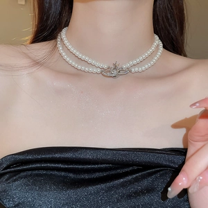 Detail view of double-layer pearl necklace featuring a sparkling silver Saturn orb pendant
