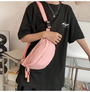 Detail view of pink canvas crossbody bag showing black buckle and woven zipper pull cord