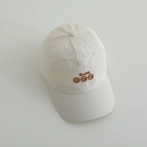 Detail of a beige kids baseball cap featuring Smile embroidery and breathable side vents