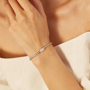 Close-up of gold-plated bracelet with rectangular light blue gemstone and zircon accents