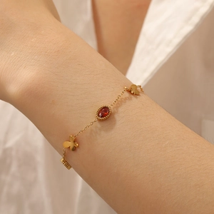 Detailed close-up of gold butterfly bracelet with red gemstone on a model wrist
