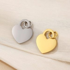 Macro shot of silver and gold heart pendants on elegant beige silk fabric texture