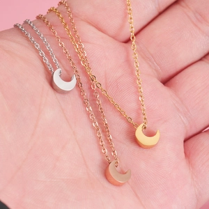 Colliers avec pendentif lune en argent, or et or rose sur un fond rose doux