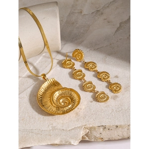 Detail view of 18k gold conch pendant necklace and shell earrings on stone background