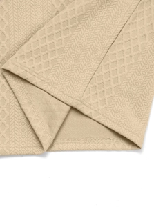 Macro shot of beige textured knit fabric with geometric patterns and neat hem stitching