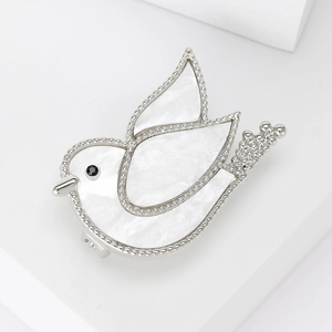 Elegant shell dove brooch with silver beaded edges and black gem eye on white pedestal