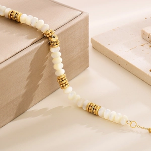 Close-up of gold plated stainless steel beaded necklace with white pearls on stone