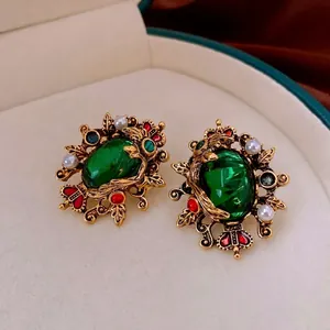Vintage emerald and pearl drop earrings in a gold-tone royal court style display