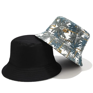 Détail du chapeau bob réversible en noir uni et imprimé de feuilles de palmier tropicales